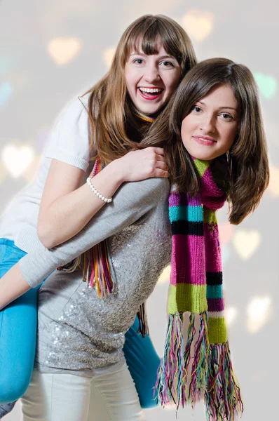 Young female riding on her sisters back — Stockfoto