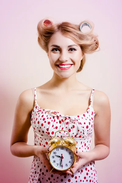 Female with haircurlers holding retro clock in studio — Stockfoto