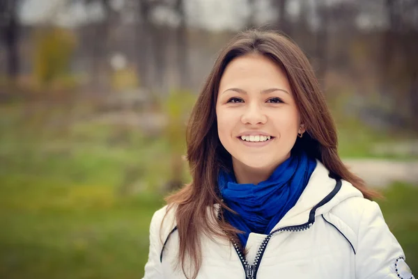 Bella ragazza bruna in giacca bianca sorridente nel parco — Foto Stock