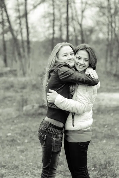 Two beautiful young girls hugging in the spring park — Stock Photo, Image