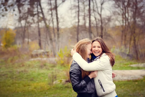 Zwei glückliche Teenager-Mädchen, die sich im Frühling im Park umarmen — Stockfoto