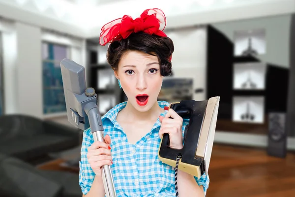 Young pretty pin-up house wife holding iron and hoover standing apartment — Stock Photo, Image