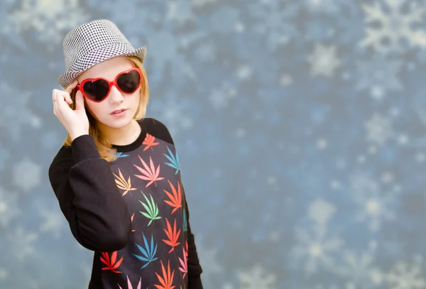 Beautiful woman in fancy sunglasses smiling on snowflakes blurred background — Zdjęcie stockowe