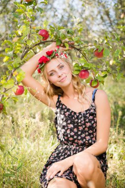 pretty blond apple fairy under branch of ripe red fruits