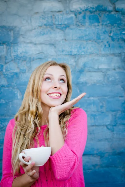 Happy exciting girl holding cup of beverage over brick wall. — Stock Photo, Image