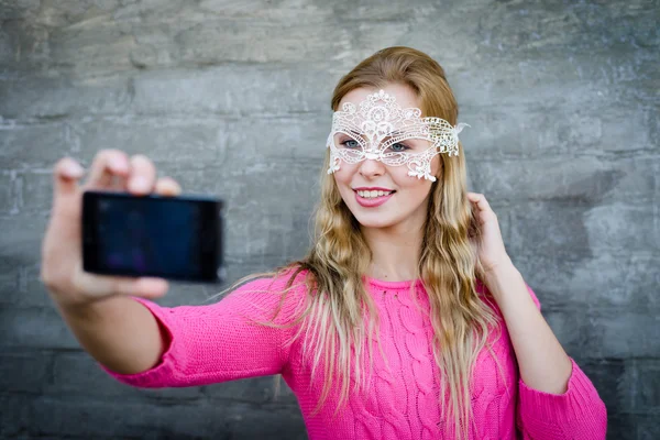 Beautiful young stylish woman making self photo wearing mask — Stock Photo, Image