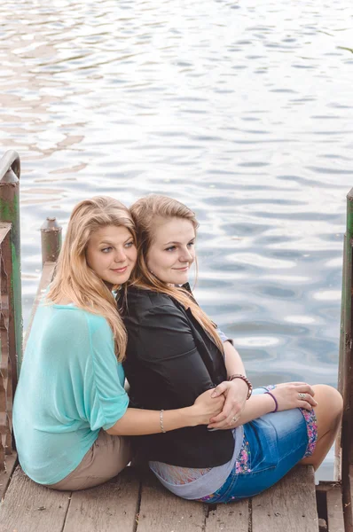 Beste vrienden, zittend op de brug door de rivier — Stockfoto