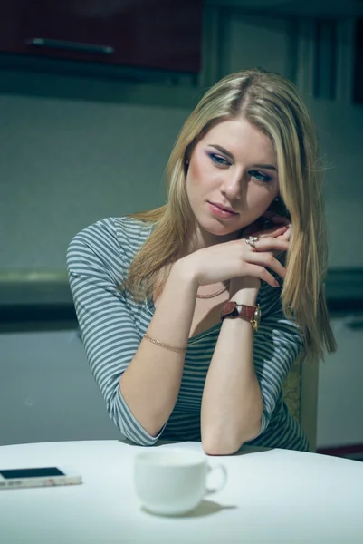 Giovane donna aspetta al telefono in una cucina notturna — Foto Stock