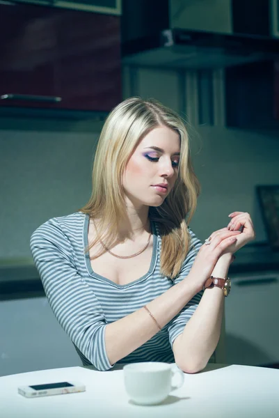 Молодая женщина ждет у телефона на ночной кухне — стоковое фото