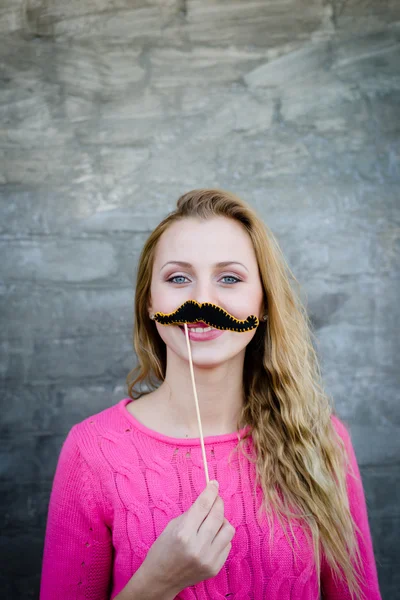 Pretty woman with long blond hair holding moustache on stick — Stock Photo, Image