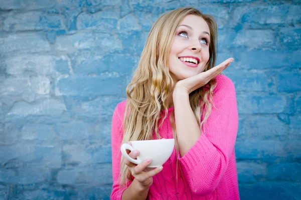 Feliz chica emocionante sosteniendo la taza de bebida sobre la pared de ladrillo . — Foto de Stock