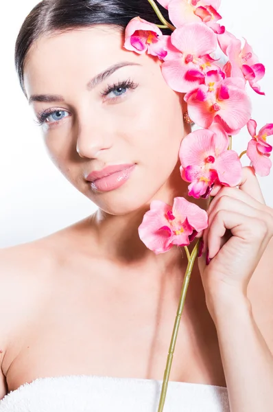 Vacker kvinna med en gren av orkidé blommor — Stockfoto