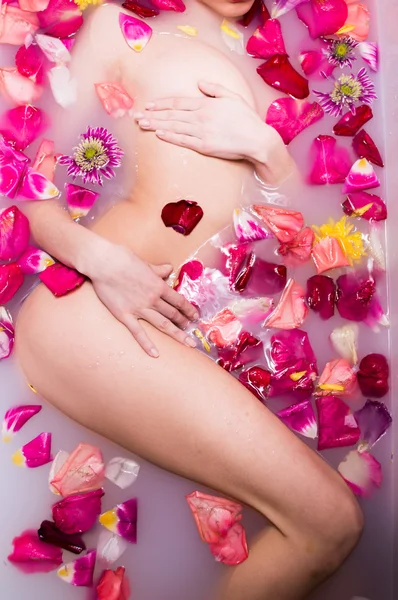 Гламурная женщина с шелковой кожей, купающаяся в лепестках роз — стоковое фото