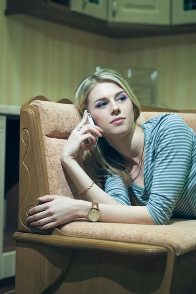 Young woman sitting alone and talking on phone — Stock Photo, Image