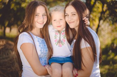 Sarılma ve sevinçle gülümseyen yaz Park'ta üç mutlu kız kardeşi