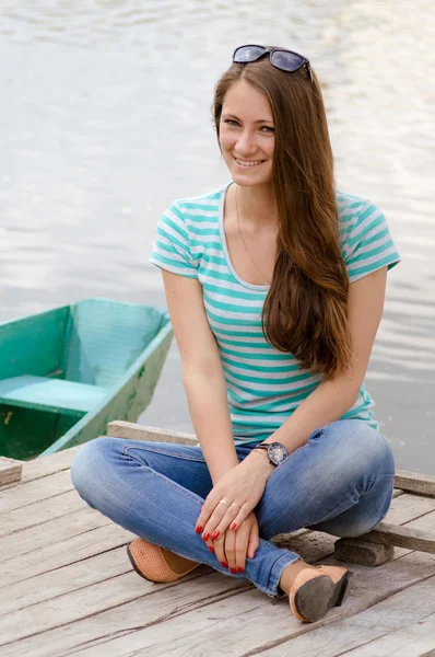 Beautiful sexy female wearing sailor striped dress sitting near boat — Stock Photo, Image