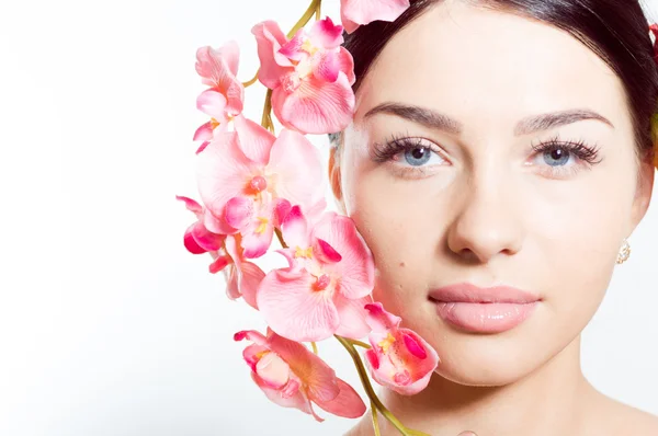 Beautiful woman holding a branch of orchid flowers — Stock Photo, Image