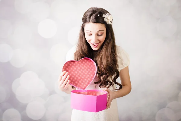 Красивая юная леди смотрит на коробку сердца на боке фоне — стоковое фото