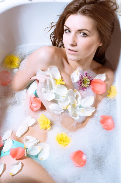 Güzel seksi genç kadın çiçek yaprakları ile banyoda — Stok fotoğraf