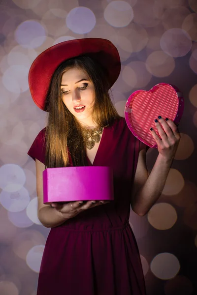 Hermosa joven mirando la caja del corazón sobre fondo bokeh —  Fotos de Stock