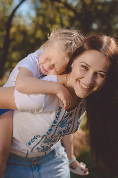 Beautiful young woman carries on her back little sister — Stock Photo, Image