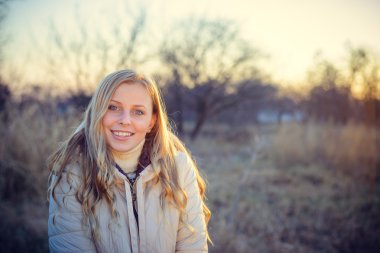 Gülümseyen genç kadın mavi gözleriyle kameraya bakıyor