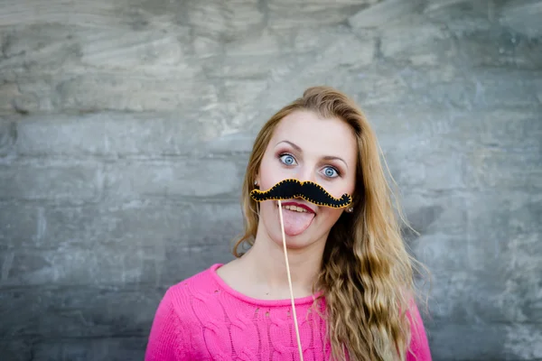 Смішна красива жінка з довгим волоссям тримає вуса на паличці — стокове фото