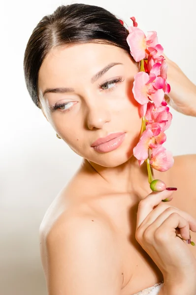 Mulher bonita segurando um ramo de flores de orquídea — Fotografia de Stock