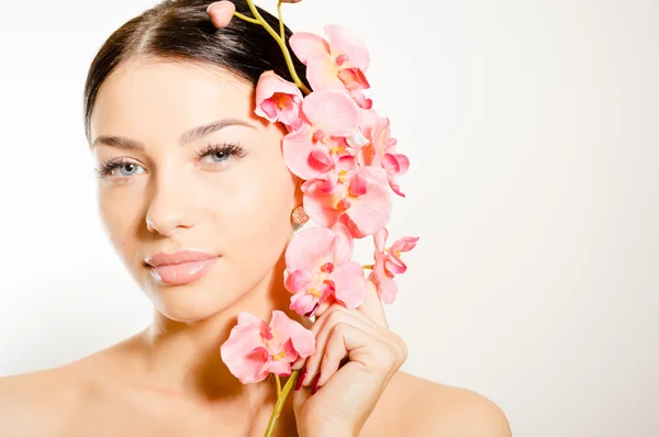 Schöne Frau mit einem Zweig Orchideenblumen — Stockfoto