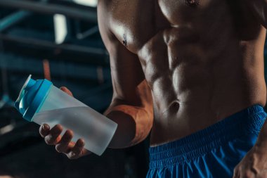 Çalkalayıcıda protein içeceği olan kaslı adam.
