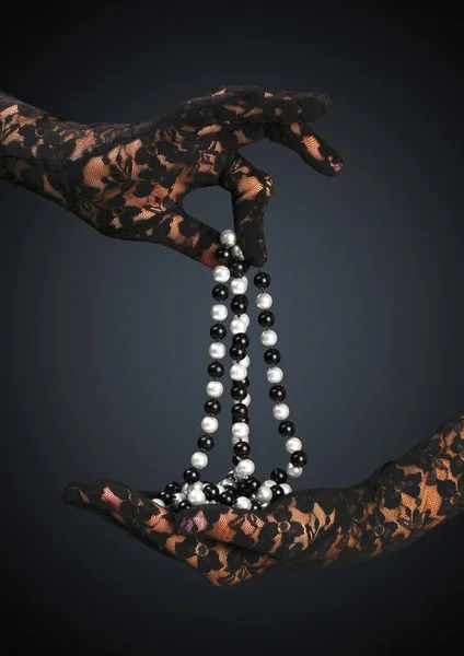 Mãos enluvadas segurar colar de jóias, no fundo escuro — Fotografia de Stock