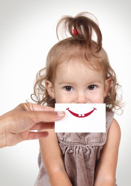 Mutlu neşeli bebek kız yüzünü gülümseme ve te ile el ile gizleme