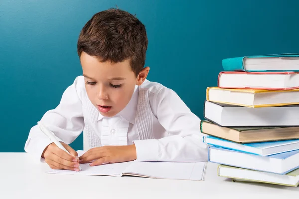 Nachdenklicher süßer Junge mit Hausaufgaben sitzt an einem Tisch — Stockfoto