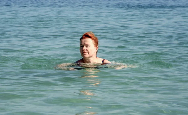 Woman with red hair swims in the ocean — Stock Photo, Image