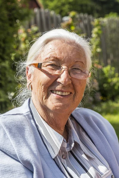 Senior mulher sentada em seu jardim — Fotografia de Stock