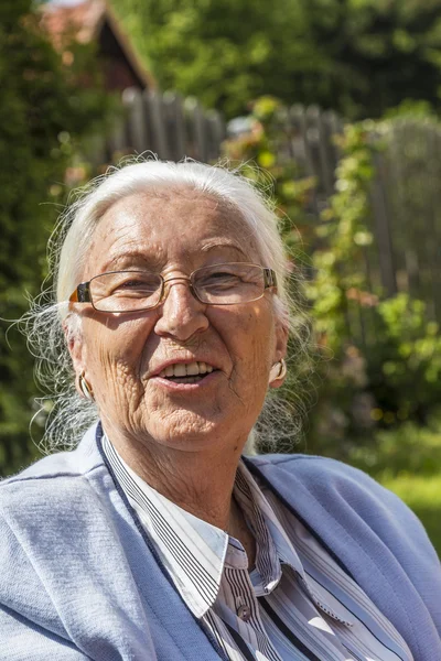 Donna anziana seduta nel suo giardino — Foto Stock