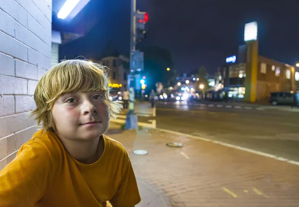 Cute boy smiles tired while sitting outside by night — Stock Photo, Image