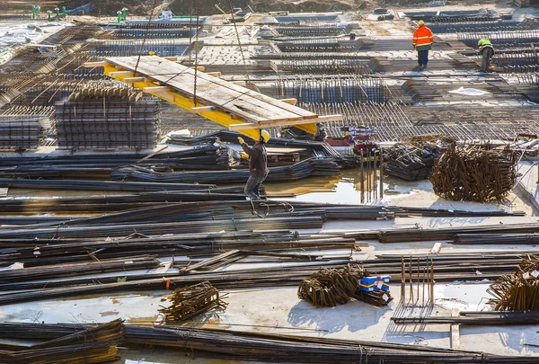 Arbeiter helfen dem Kran, Baumaterial zur Baustelle zu transportieren — Stockfoto