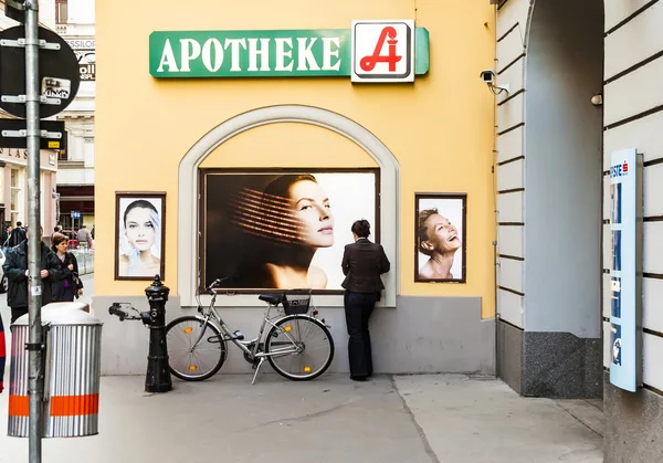 Žena stojí na zeď a sleduje plakáty pro péči o vlasy žen — Stock fotografie