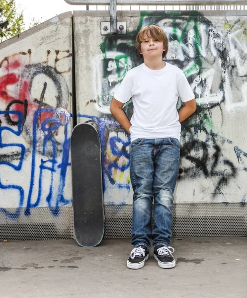 Niño se relaja con su tabla de skate en el parque de skate —  Fotos de Stock