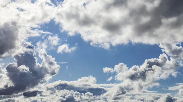 Kumuluswolken und graue Gewitterwolken sammeln sich am blauen Himmel — Stockfoto