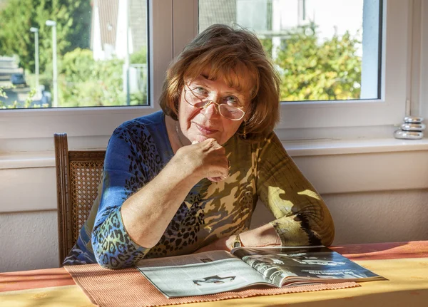 Ältere attraktive Frau liest in einer Zeitschrift — Stockfoto