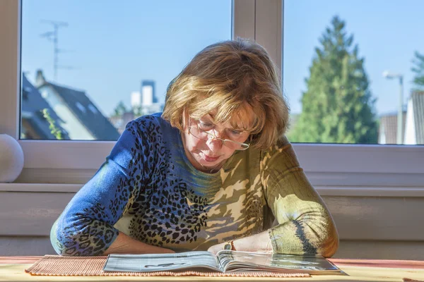 Ältere attraktive Frau liest in einer Zeitschrift — Stockfoto