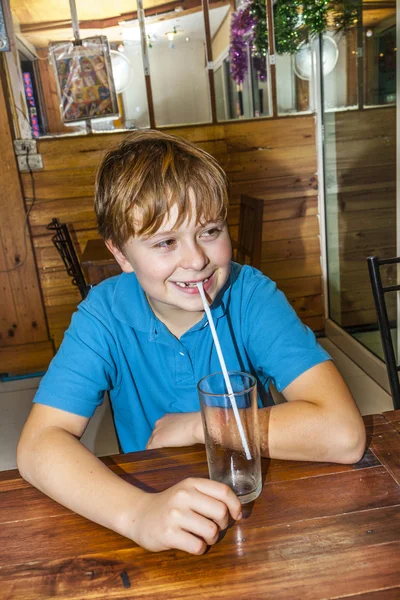 Chico en un restaurante y usando una pajita para beber —  Fotos de Stock
