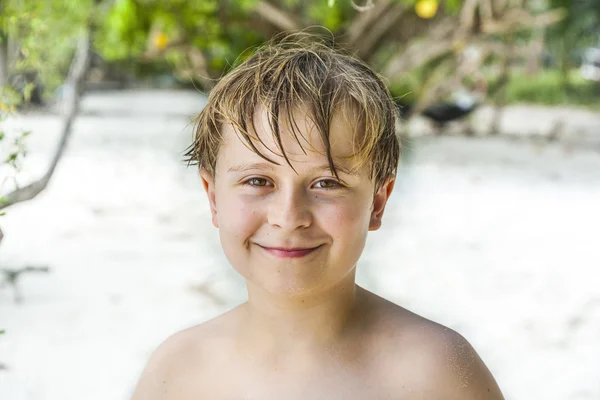 Lycklig pojke med blött hår på stranden — Stockfoto