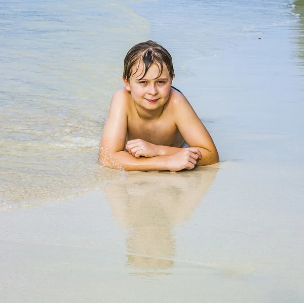 Menino está deitado na praia — Fotografia de Stock