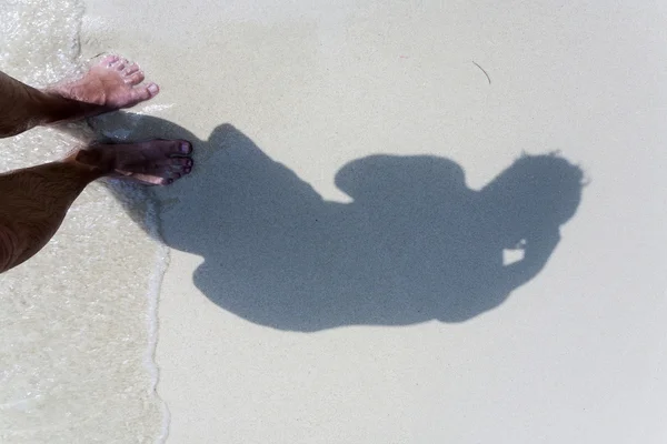 Hombre está arrojando sombra a la arena fina de la playa, mostrando el cuerpo completo en un círculo de suavidad —  Fotos de Stock