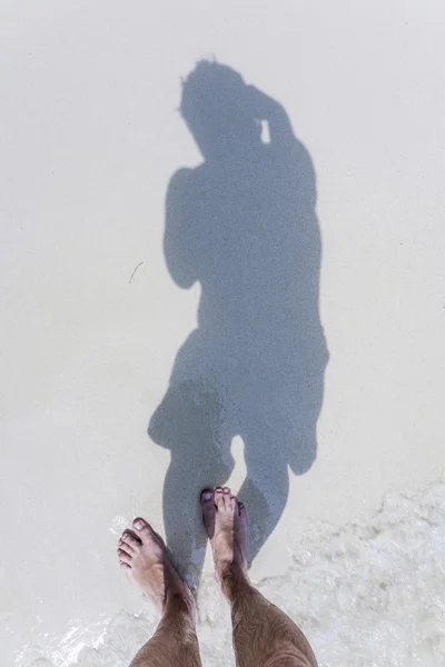 L'homme jette l'ombre sur le sable fin de la plage — Photo