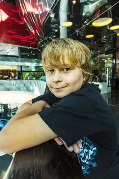 Boy resting at a balustrade in a modern shopping center — Stock Photo, Image
