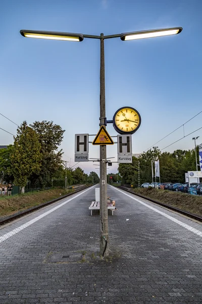 Personas sentadas en un banco y esperando el próximo tren o S-Bahn —  Fotos de Stock